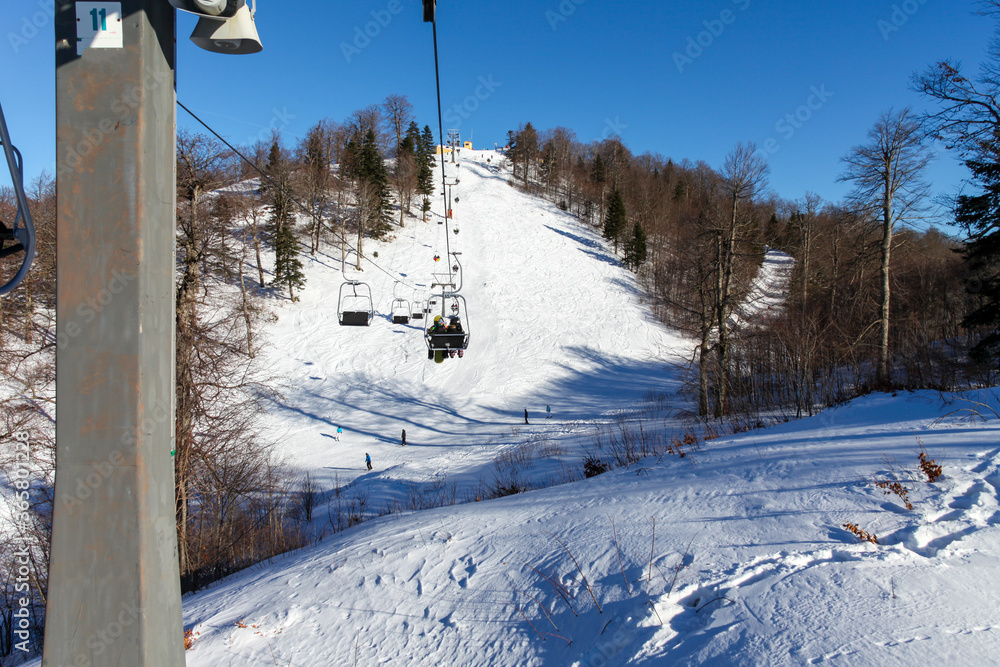 Obraz premium Ski lifts in a ski center taking skiers up the hill. Skiing and winter sports concept. Vacation in the mountains with friends and family. Winter holiday.