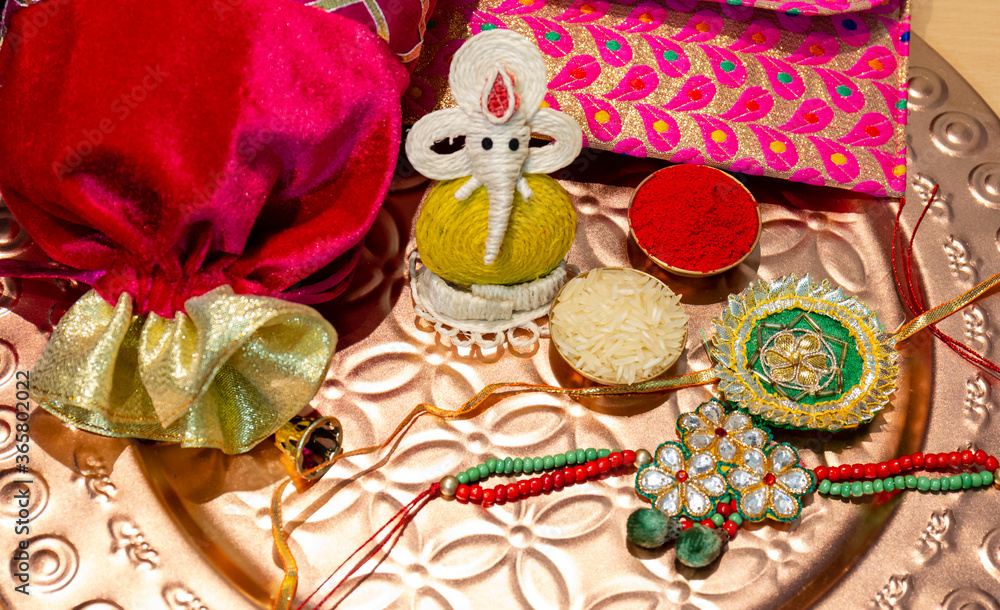 Indian festival, Raksha Bandhan background with an elegant colorful Rakhi, Gift, Rice Grains and Kumkum. A traditional Indian wrist band which is a symbol of love between Brothers and Sisters.
