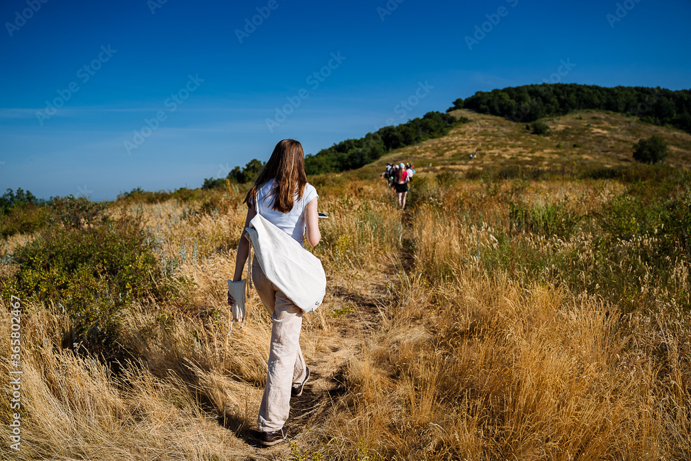 people climb up the mountain on a path among the bushes, feet close-up, shooting shoes while walking, white sneakers, outdoors, trekking, Hiking in nature, yellowed grass people climb up the mountain on a path among the bushes, feet close-up, shooting shoes while walking, white sneakers, outdoors, trekking, Hiking in nature, yellowed grass