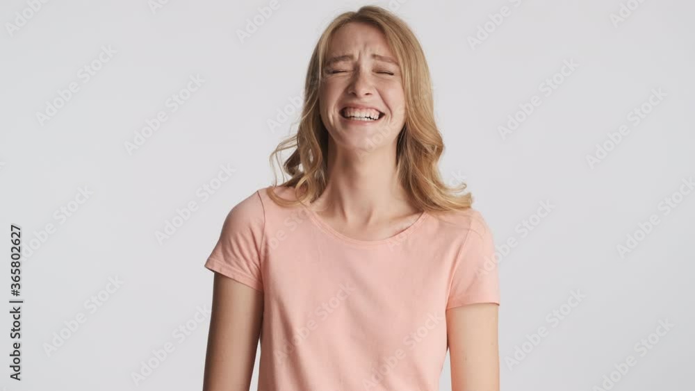 Beautiful cheerful blond girl emotionally laughing on camera over gray background. Happy expression Beautiful cheerful blond girl emotionally laughing on camera over gray background. Happy expression