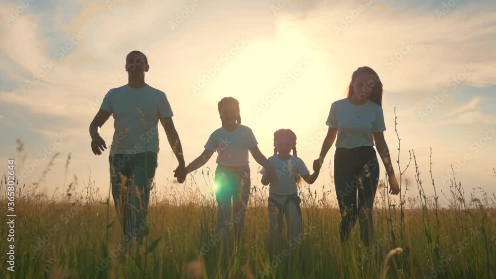 Happy family together. People hold hands on a walk on the green grass. The concept of teamwork. Happy father with daughters. Happy family together. People hold hands on a walk on the green grass. The concept of teamwork. Happy father with daughters.