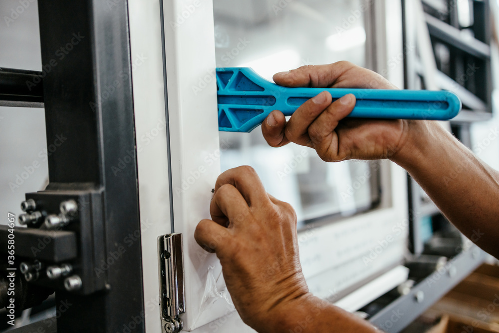 Manual worker assembling PVC doors and windows. Manufacturing jobs