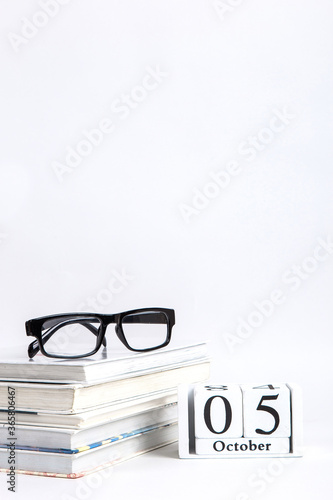 Books, glasses and calendar with date of October 5, on a white background, Teacher's Day concept. Copy space.