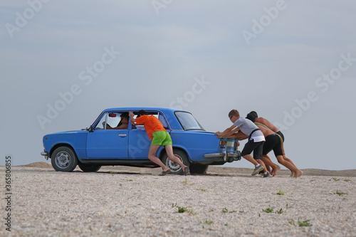 group of people push the car in the desert photo