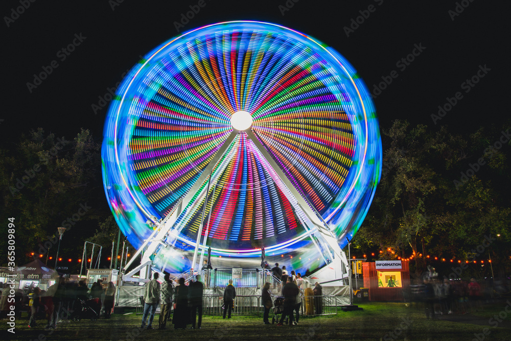 Colourful ferris wheel spinning at night 