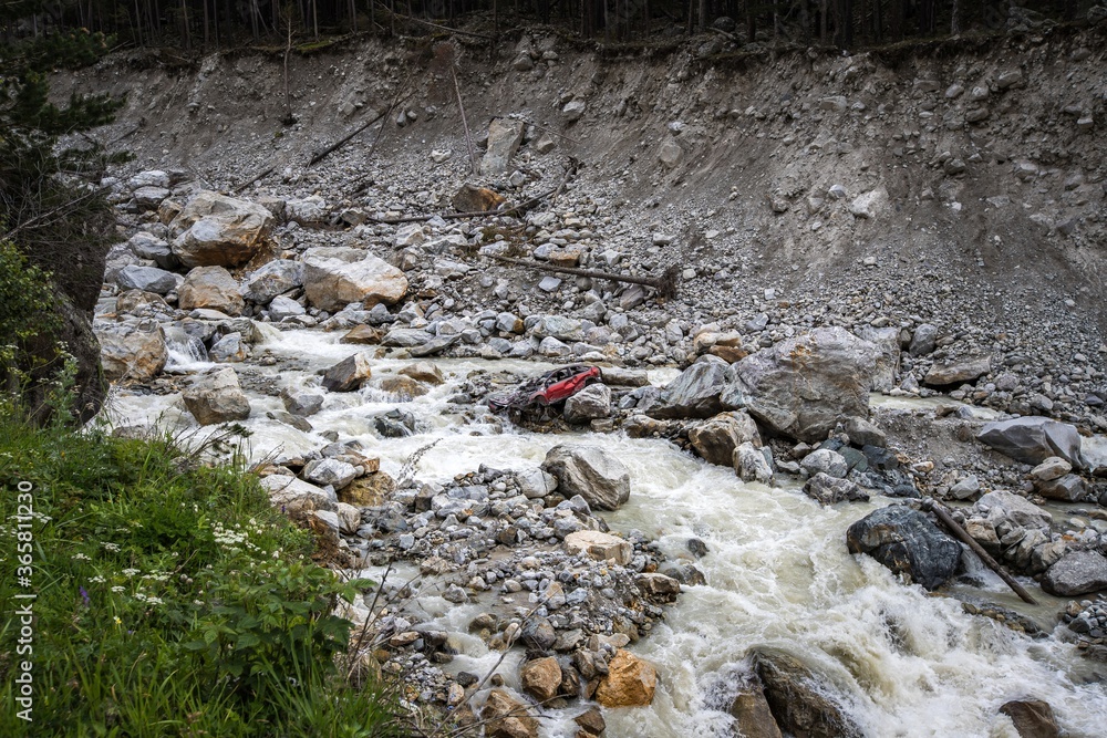 Red car broken and flushed by great mudslide. Rocky Adyl Su river in Caucasus. Kabardino-Balkaria, Russia. Red car broken and flushed by great mudslide. Rocky Adyl Su river in Caucasus. Kabardino-Balkaria, Russia.