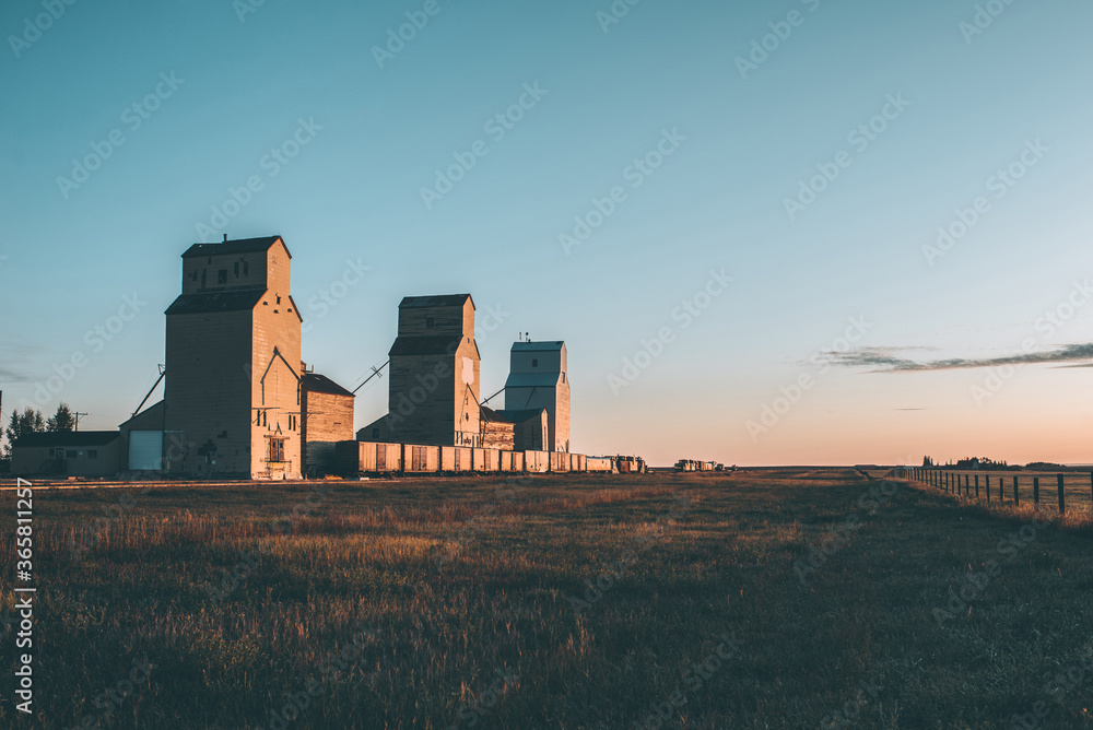 Grain silos and rail cars at sunrise on the prairies 