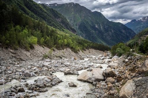 Stony riverbed of Adyl Su river, high green Caucasus mountains on the background. Kabardino-Balkaria, Russia.