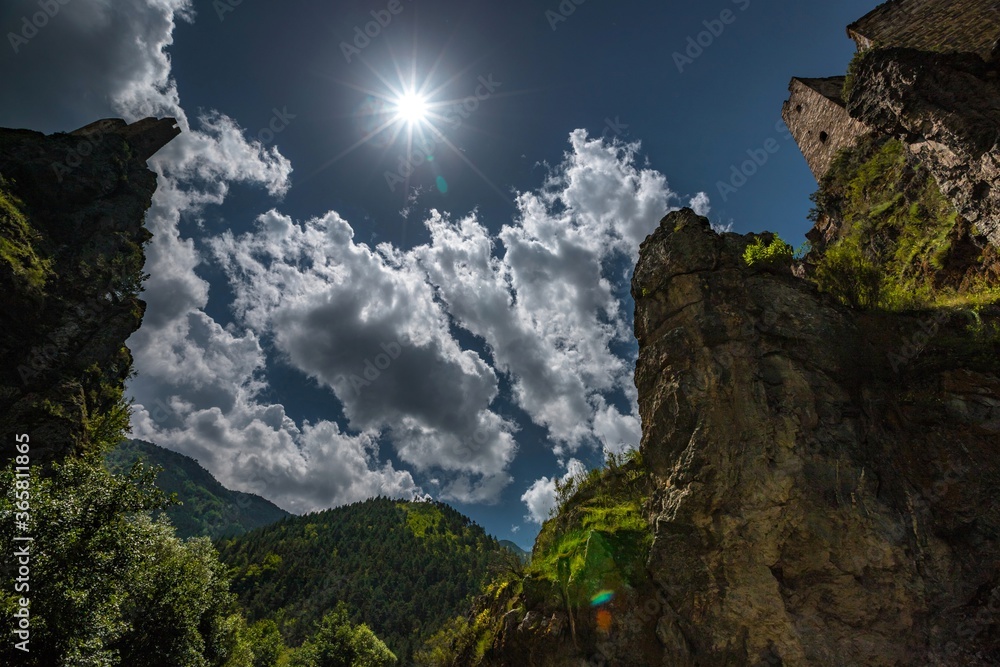 Great shot of blue summer sky and bright sun between tops of two castles of  Vovnushki medieval tower complex. The Caucasus, Ingushetia, Russia.
