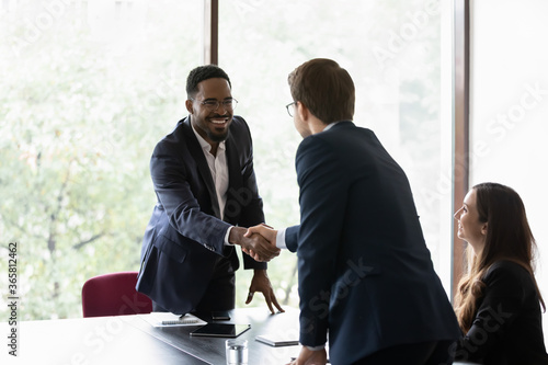 Foto Mixed race and Caucasian business partners start group meeting shake hands express regard