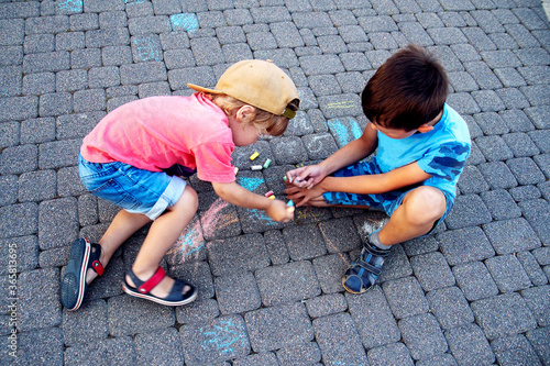 Two boys draw with chalk on the pavement. The concept of a happy childhood.