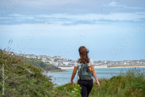 Woman walking on the South West Coastal Path in Cornwall, England with St Ives in the background 