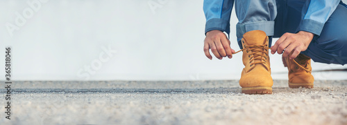 Banner man kneel down tie shoes lace on industry worker boots. Close up shot of man hands tied shoestring for his construction brown boots. Close up man hands tie up shoes with empty blank copy space