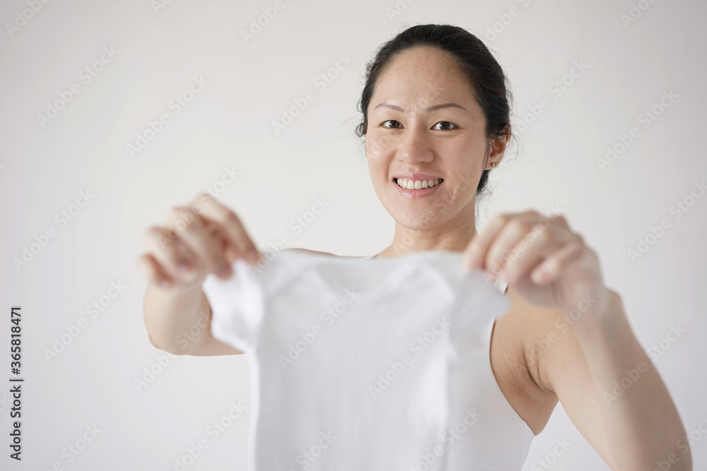 Asian Chinese new pregnant mum holding up an infant clothing Asian Chinese new pregnant mum holding up an infant clothing