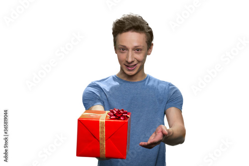 Caucasian teen boy is giving you red gift box. Isolated on white background.