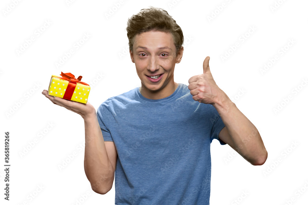 Teenage boy with gift box is showing thumb up. Isolated on white background. Teenage boy with gift box is showing thumb up. Isolated on white background.
