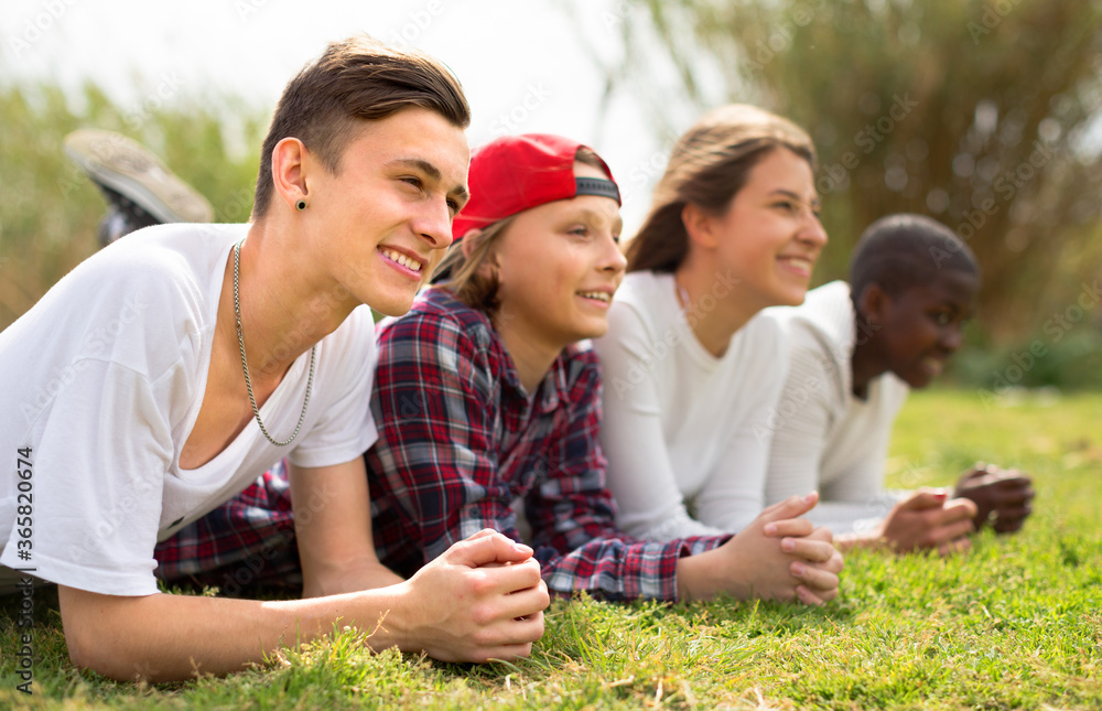 multinational modern teens lie in the park on the grass multinational modern teens lie in the park on the grass