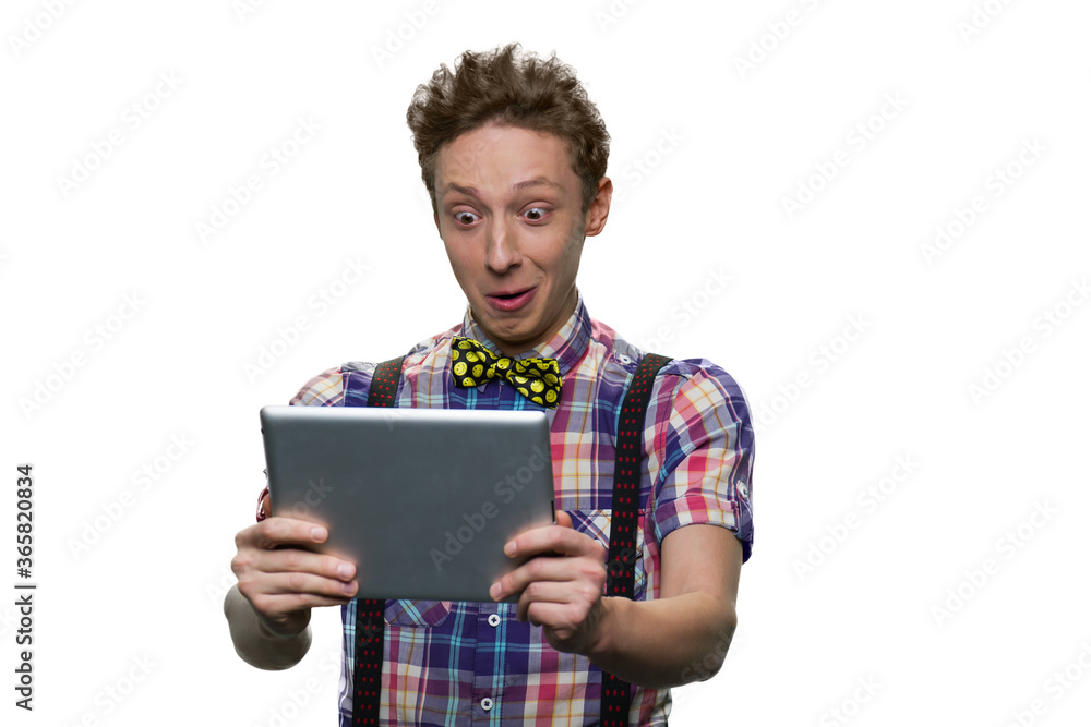 Extremely surprised teenage boy's looking at tablet pc screen. Widely opened eyes. Isolated on white background. Extremely surprised teenage boy's looking at tablet pc screen. Widely opened eyes. Isolated on white background.