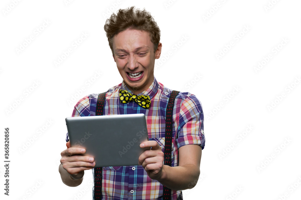 Stressed crying teenage boy is looking at tablet pc screen. Sadness and desparation. Isolated on white background. Stressed crying teenage boy is looking at tablet pc screen. Sadness and desparation. Isolated on white background.