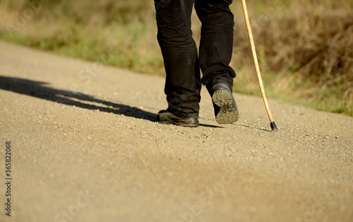 .Feet of man and hiking stick on a path © Alejandro