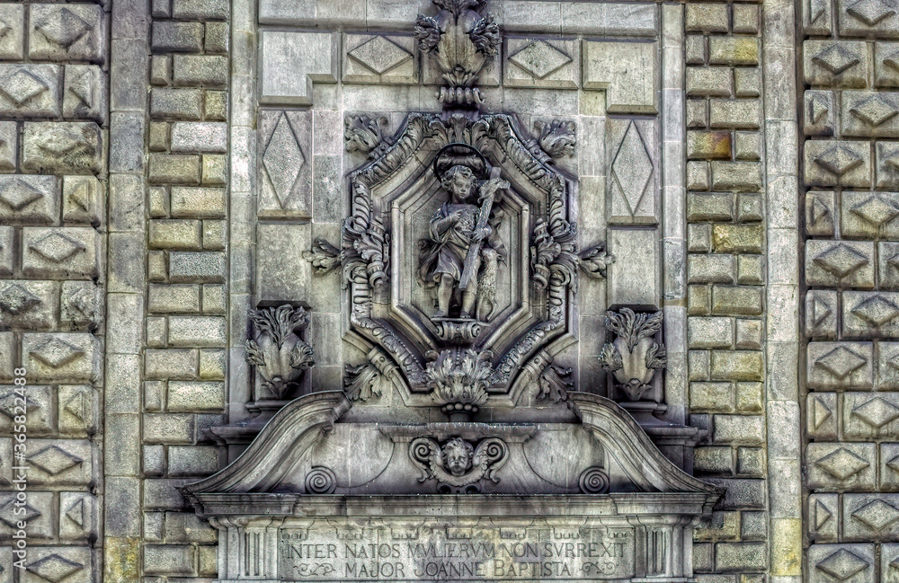 Bas relief sculpture of little boy with cross at facade of religious building in Barcelona, Spain.
