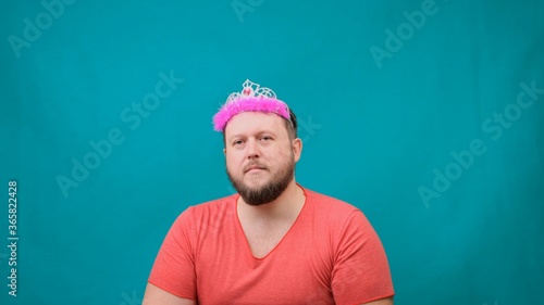 Playful bearded freaky man in a pink T-shirt with a deadema on his head sad with a magic wand in his hand. A funny wizard joke to make and fulfill a wish. photo