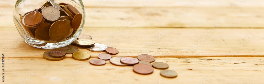 Glass jar with coins, on a wooden background, top view. Finance and investment concept. Glass jar with coins, on a wooden background, top view. Finance and investment concept.