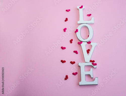 Valentine's Day. Word love made of wooden letters with a decor of hearts. The concept of congratulation of lovers. Copy space.