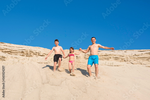 Happy family run from the sandy mountain. Family summer vacation, Outdoor activity, lifestyle.
