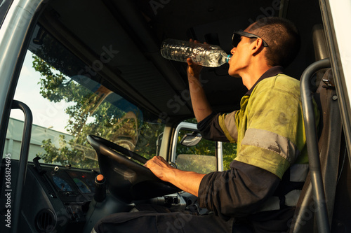 Young truck driver drinking water at work