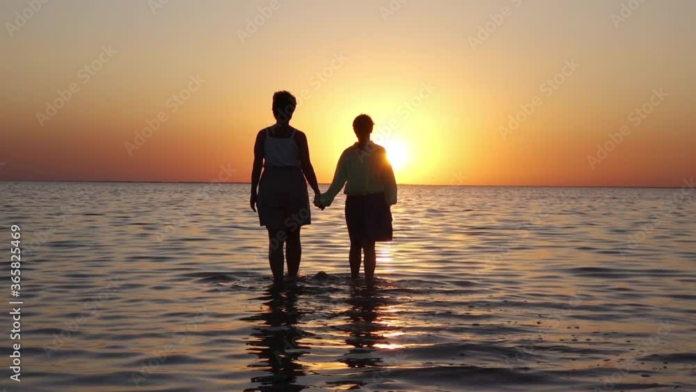 two people walk on water at sunset two people walk on water at sunset