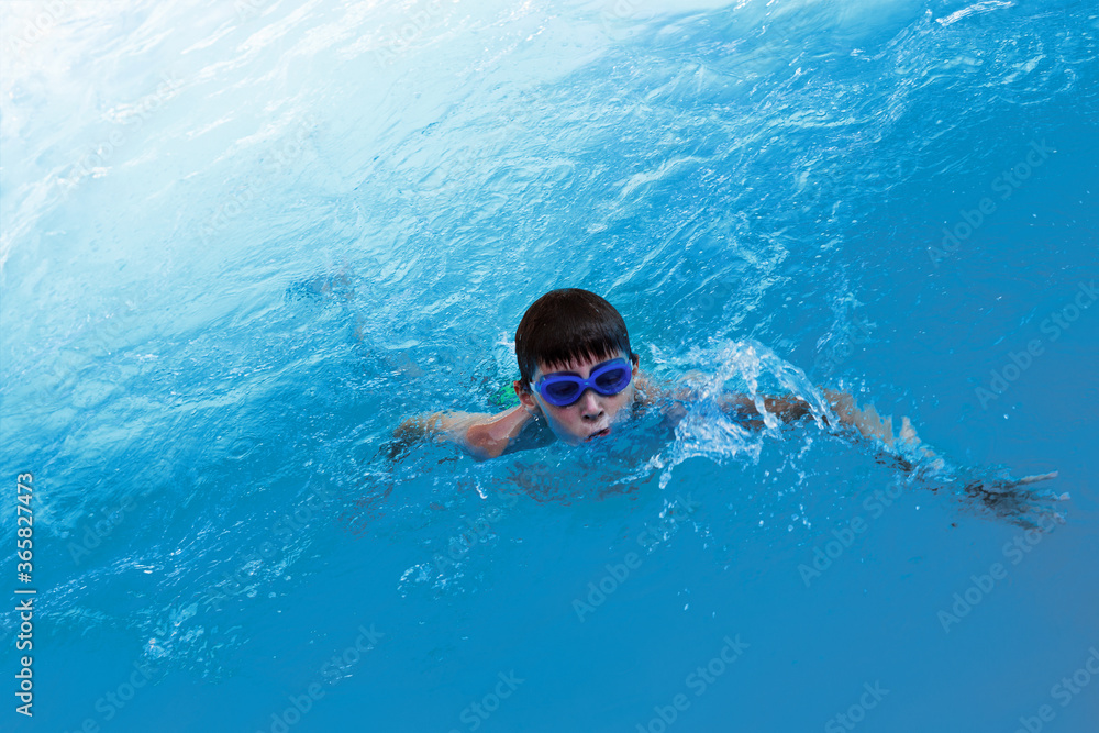 Little boy athlete swims in the pool by the crawl. The concept of training and children's sports