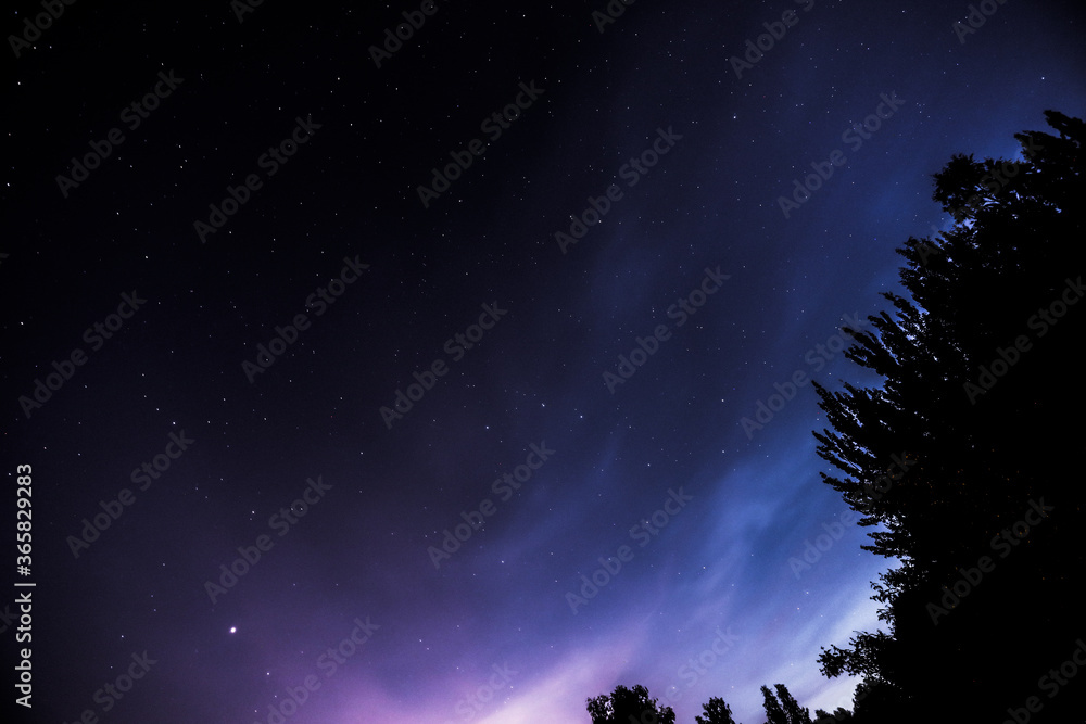 View of a night blue and purple sky with a stars in the countryside.