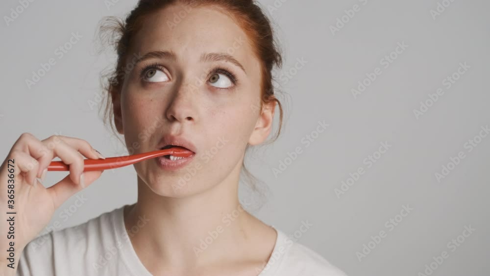 Close up beautiful girl happily brushing teeth on camera over white background Close up beautiful girl happily brushing teeth on camera over white background