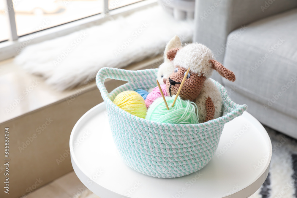 Wicker basket with toys and knitting yarn on table in room Wicker basket with toys and knitting yarn on table in room