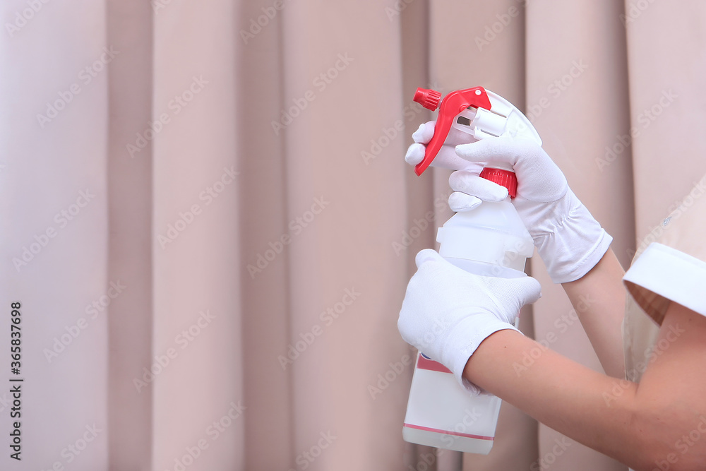 The maid sprays air freshener from a plastic bottle. Hands in white cotton gloves. An unrecognizable photo. Copy of the space. The concept of the hotel business. The maid sprays air freshener from a plastic bottle. Hands in white cotton gloves. An unrecognizable photo. Copy of the space. The concept of the hotel business.