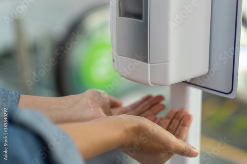 Obraz na płótnie Close up of woman holding hands under automatic sanitiser dispense
