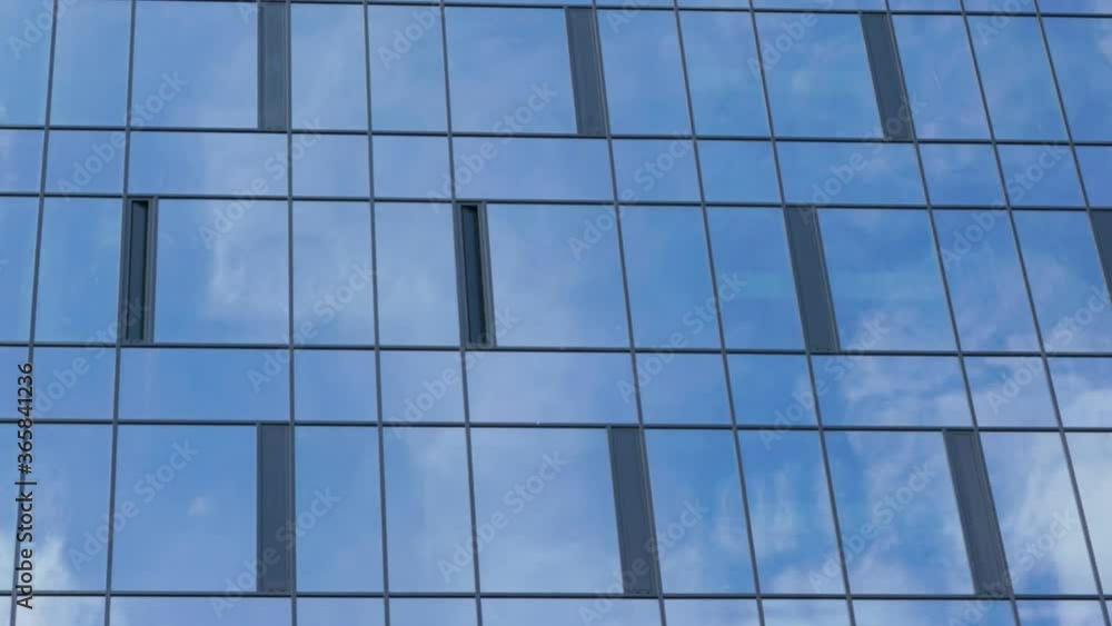 local office building with large windows reflects white clouds driven by light summer wind across sky time lapse zoom out