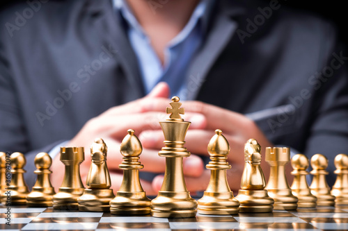 Golden chess pieces on chess board and in front of businessman.Business competition and marketing strategy planing concept.