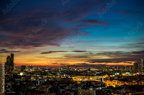 The high angle background of the city view with the secret light of the evening, blurring of night lights, showing the distribution of condominiums, dense homes in the capital community © bangprik