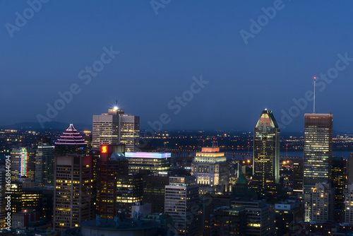 A skyline view of a city illuminated skyscrapers, buildings, and streets taken from a mountain at twilight time, Montreal, QC, Canada