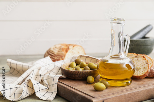 Bottle of tasty olive oil and bread on table photo