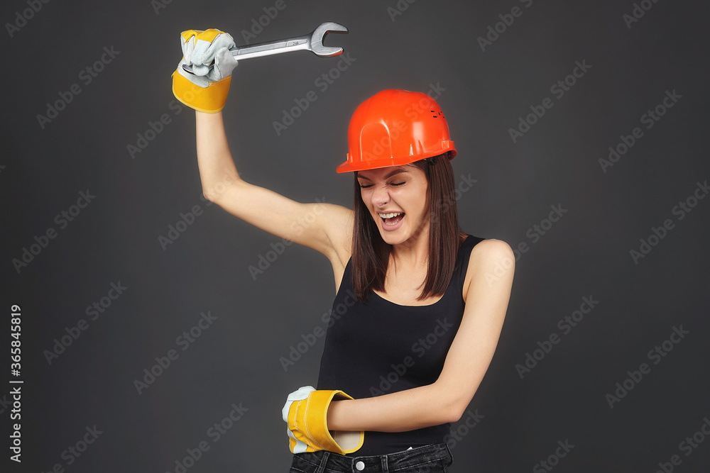 beautiful women in an orange helmet. holding a spanner in his hand. Posing while working, twisting an imaginary bolt.. beautiful women in an orange helmet. holding a spanner in his hand. Posing while working, twisting an imaginary bolt..