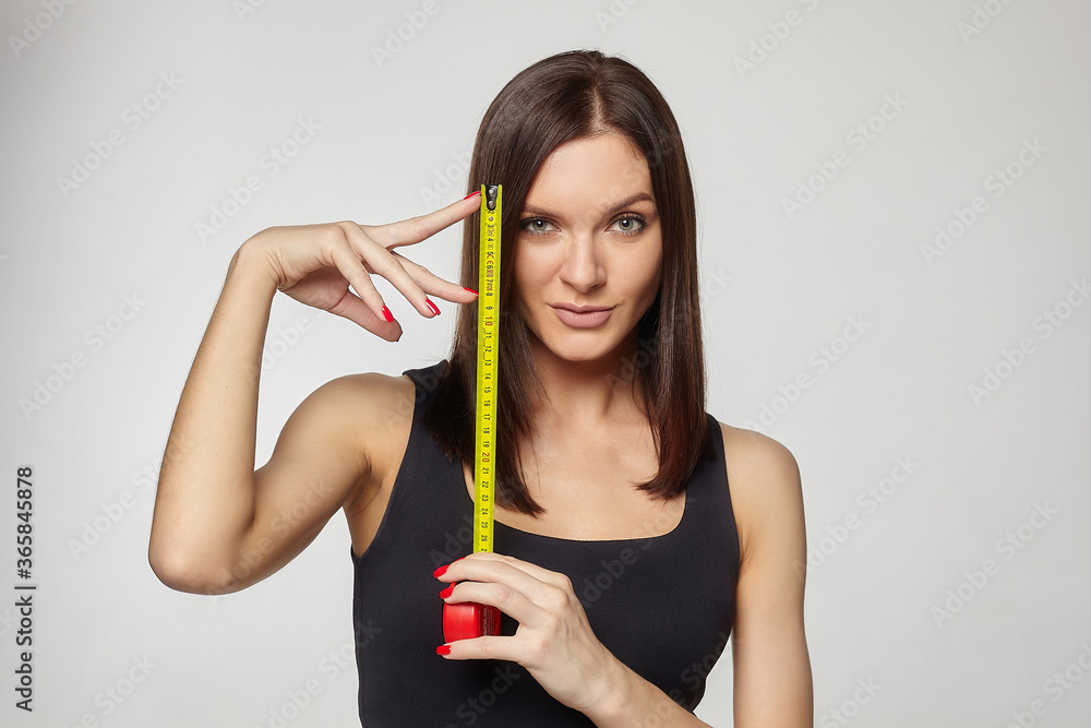 beautiful girl holds a measuring tape in her hands. the concept of imagination about the size of the penis... beautiful girl holds a measuring tape in her hands. the concept of imagination about the size of the penis...