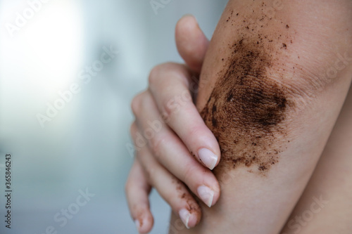 DIY Coffee scrub. Beauty skin care. Young woman putting coffee scrub on dry elbow skin.