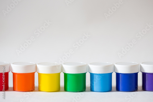 containers with paint in row on white background. multi-color acrylic rainbow. new gouache in banks