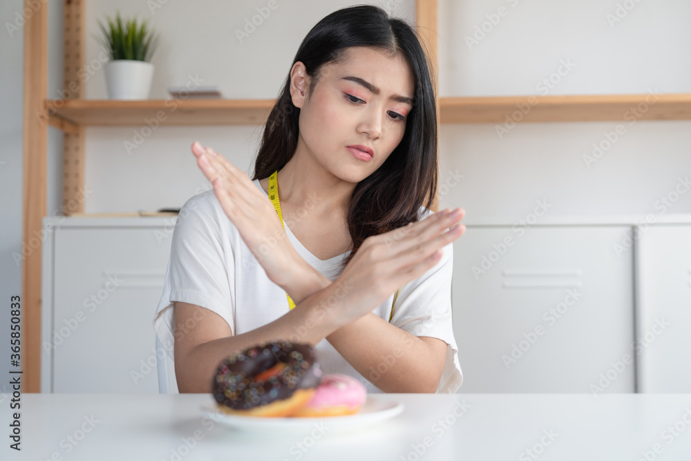 Young Asian woman on dieting refuses donuts junk food 