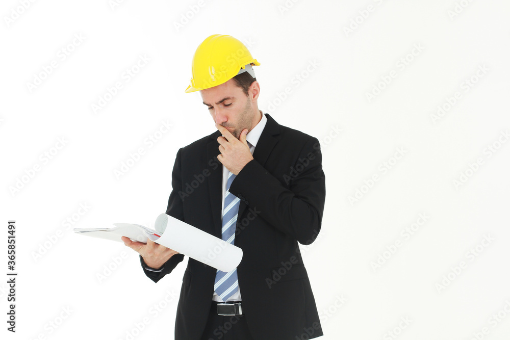 Handsome and smart engineer in black suit Wearing a yellow safety engineer hat with hand holding Construction drawing papers and serious in work isolated on yellow background. Copy Space Handsome and smart engineer in black suit Wearing a yellow safety engineer hat with hand holding Construction drawing papers and serious in work isolated on yellow background. Copy Space