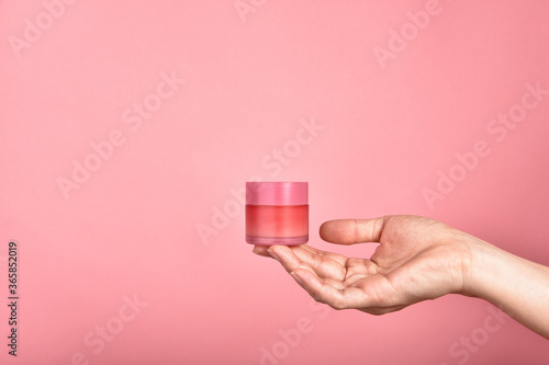Obraz na płótnie Hand showing pastel pink cosmetic containers packaging over pink background, Facial skincare cream, Blank label for branding mock-up, Beauty product concept. w salonie