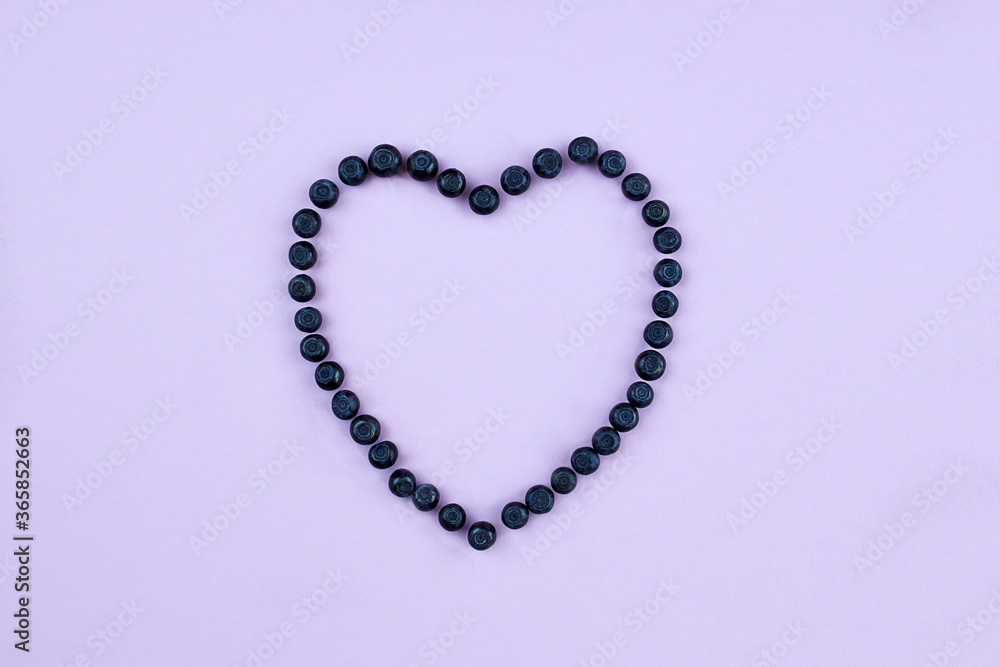 Blueberries on a lilac background, laid out in the shape of a heart